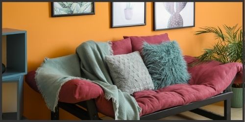 living room painted with bright orange wall, and accented with burgundy and teal. Colours inspired by "A Taste of India". 